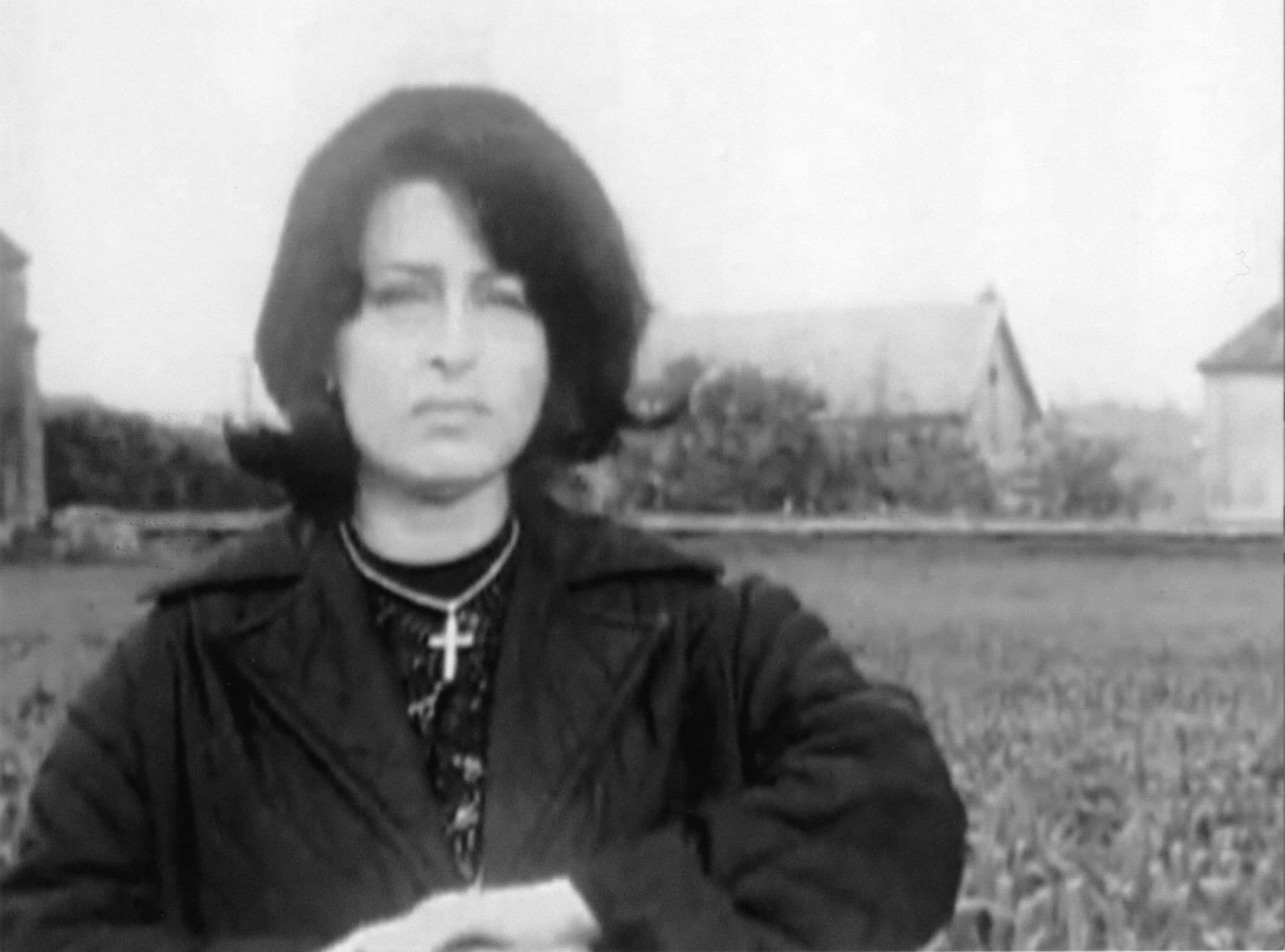 The black and white image of a woman standing in front of a rural scene.