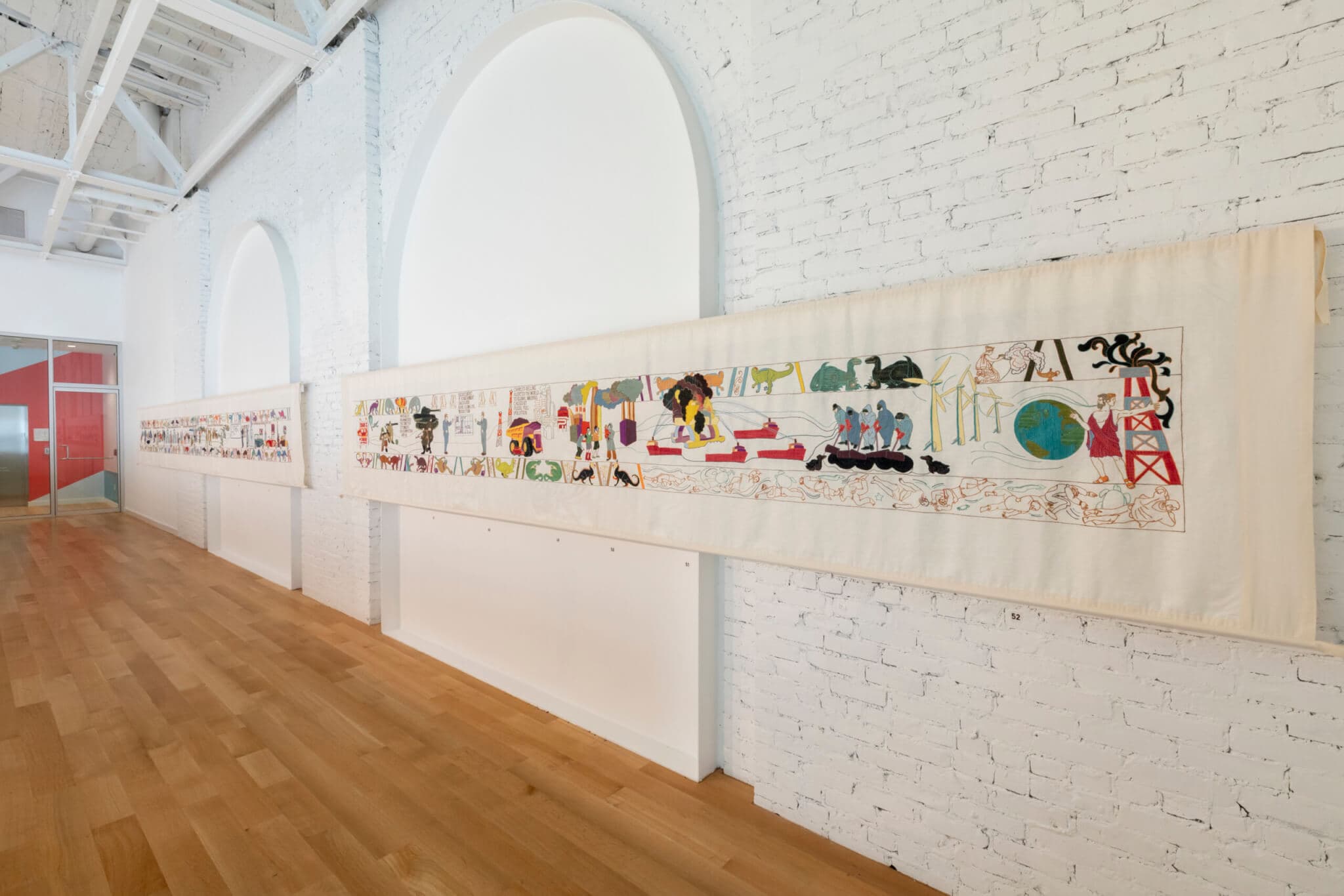 A long embroidered tapestry adorns a gallery wall.